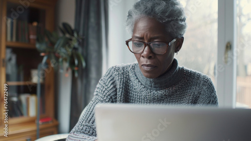 An older woman focused intently on her laptop screen, reflecting concentration and modernity.
