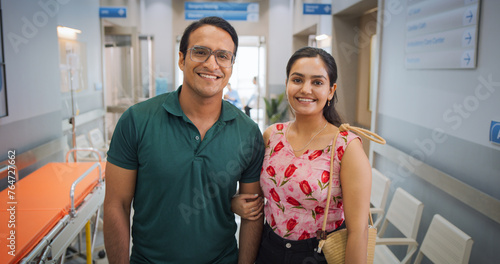 Portrait of Young Indian Couple in a Hospital Smiling and Looking at the Camera. Happy Male and Female Patients Satisfied with Healthcare Service Provided by Modern Local Medical Clinic