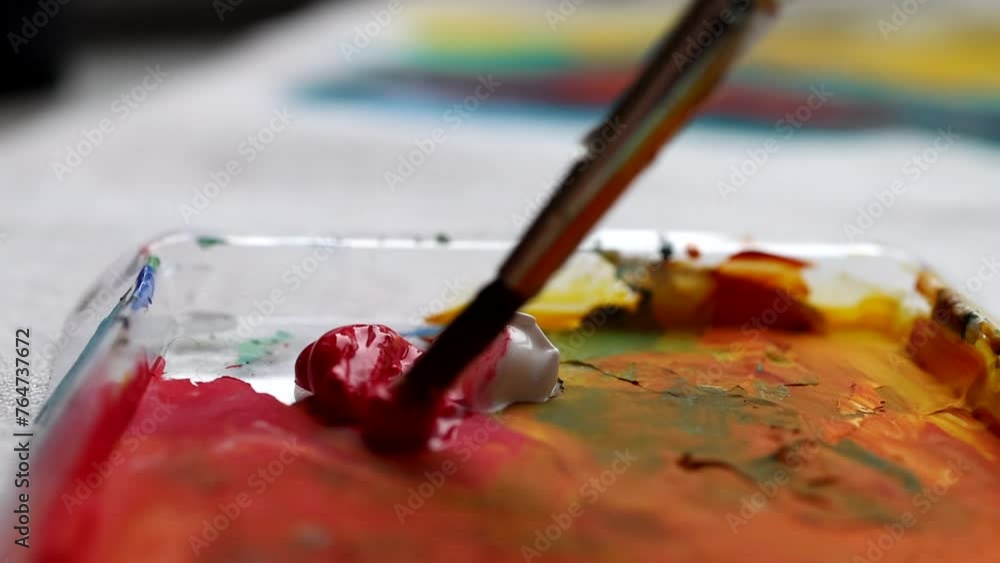 Mixing paint white and red on a colorful palette with paintbrush. Creative process close up. Artist brush and acrylic colors Mixing paint white and red on a colorful palette with paintbrush. Creative process close up. Artist brush and acrylic colors