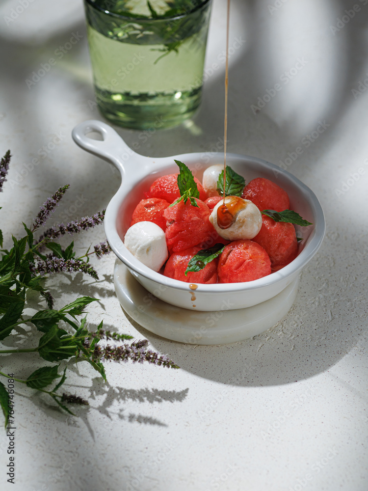 Watermelon Salad with mozzarella balls and mint on light rose background. healthy eating. Summer recipe concept Watermelon Salad with mozzarella balls and mint on light rose background. healthy eating. Summer recipe concept