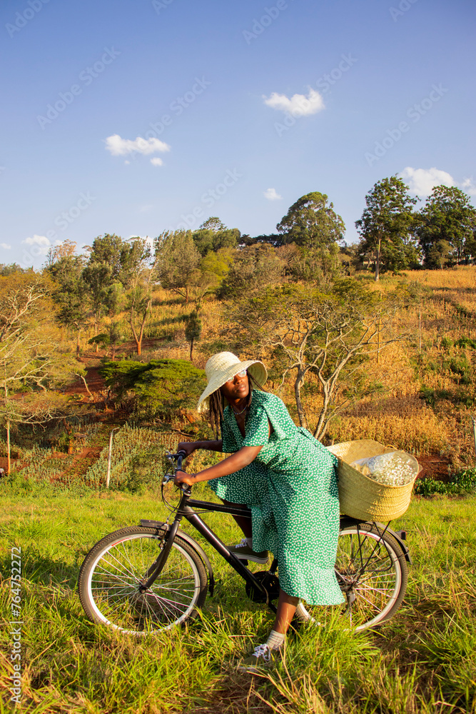 Obraz premium A young black woman riding a bicycle in a field
