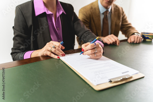 Two business professionals - engaged in signing a contract, focus on hands and document - legal agreement execution or official paperwork completion - partnership dea finalization, business attire. photo