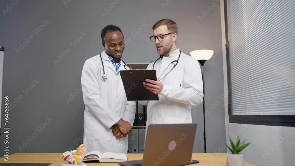 Two doctors in white lab coats discussing test results on tablet in hospital office Two doctors in white lab coats discussing test results on tablet in hospital office
