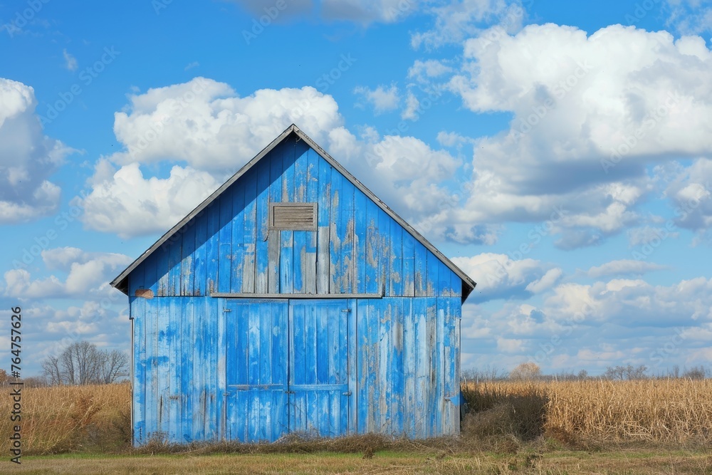 Obraz premium Vintage blue barn with a rustic appearance in a tranquil rural landscape
