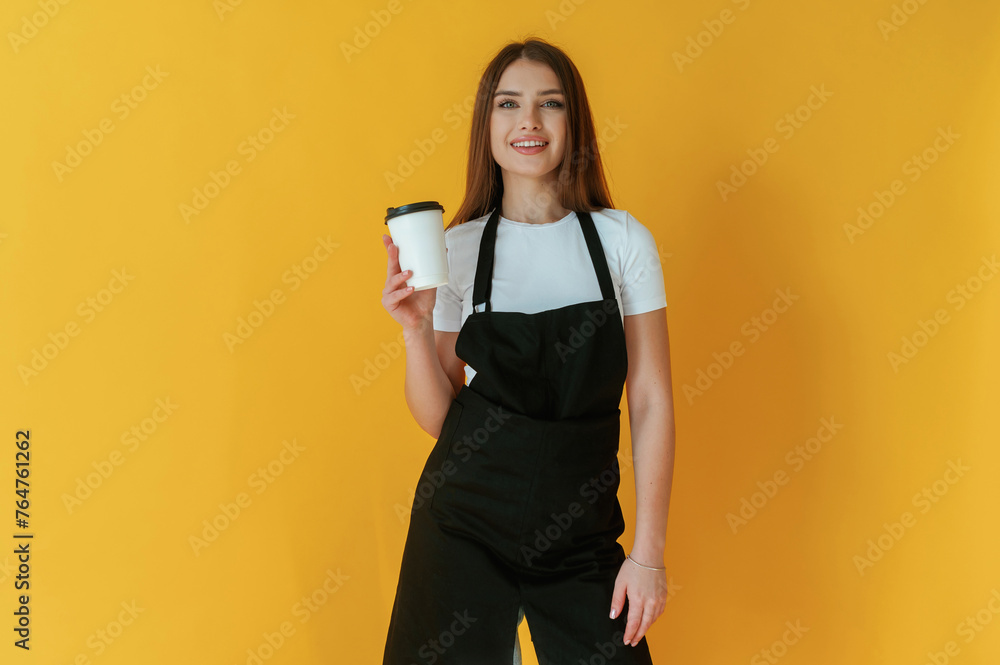 Nice coffee cup. Young woman is against yellow background Nice coffee cup. Young woman is against yellow background