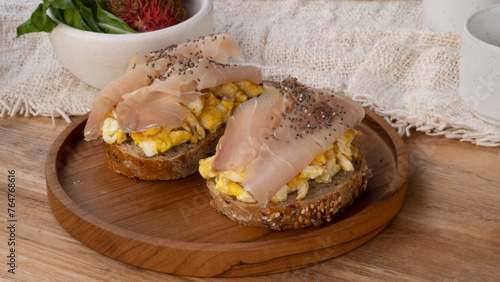 Breakfast table with high nutritions vegan and vegetable food, salmon fume with scrambled egg on top of healthy wheat bread. (ID: 764768616)