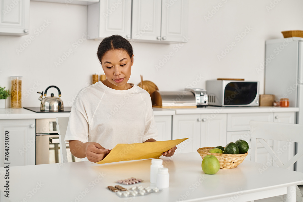 brunette african american woman opening envelope with dietary plan near supplements and fruits brunette african american woman opening envelope with dietary plan near supplements and fruits