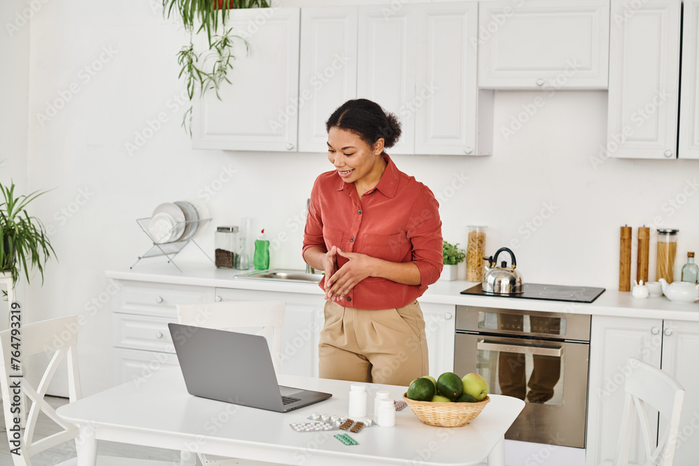 african american dietitian gesturing while standing near laptop and offering diet advice online