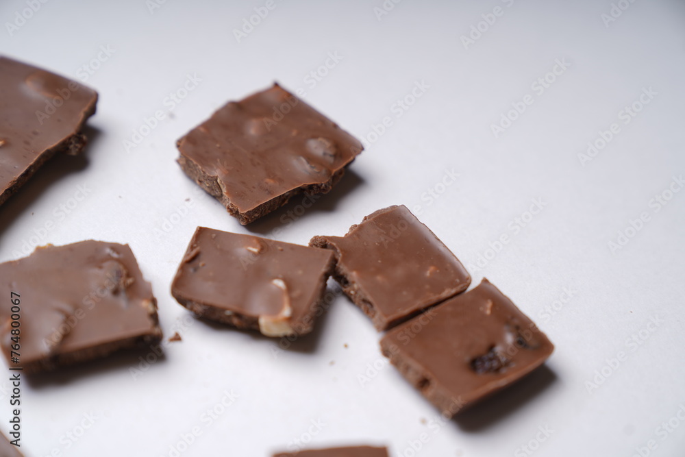 pieces of chocolate with raisins and nuts on a white table pieces of chocolate with raisins and nuts on a white table