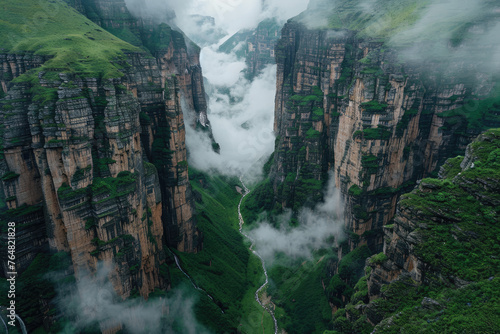 Cinematic shot of the view from above, looking down at an epic mountain range with clouds rolling over and mist hanging in between mountains, green grass on cliffs photo