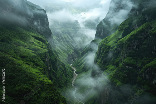 Cinematic shot of the view from above, looking down at an epic mountain range with clouds rolling over and mist hanging in between mountains, green grass on cliffs