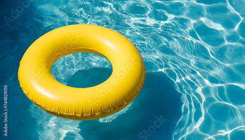 Yellow inflatable ring floating in blue swimming pool water, top view