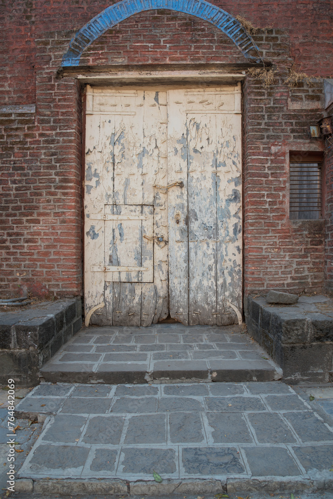 Fototapeta premium Old used wooden door in a red brick wall