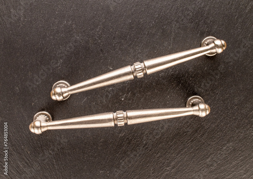 Two metal drawer handles on slate stone, furniture accessories, macro, top view.