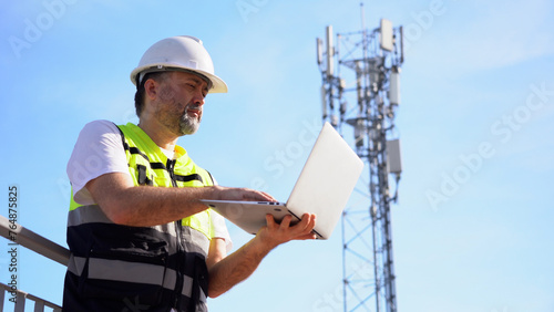 Engineer using laptop computer testing the communications tower