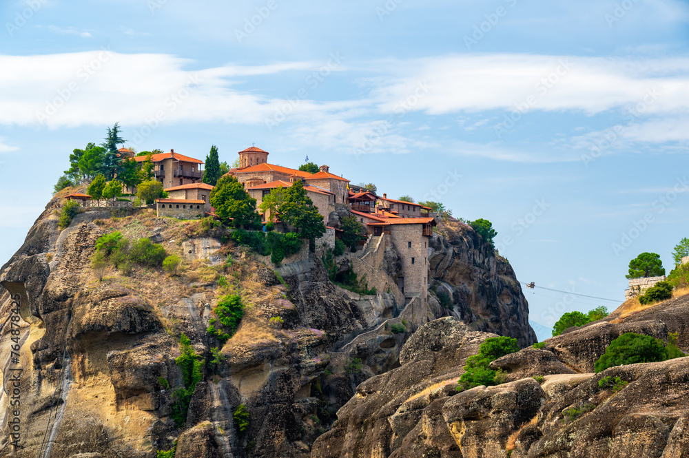 Monastery Meteora Greece. Stunning summer panoramic landscape. View at mountains and green forest against epic blue sky with clouds. UNESCO heritage list object.