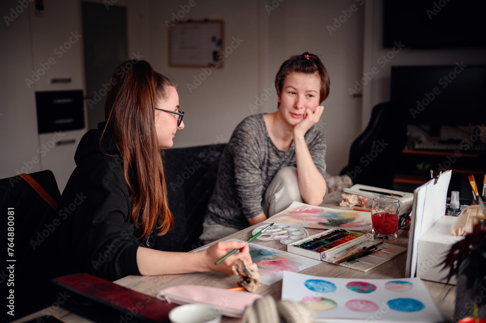 Two friends share a contemplative pause during an art-making session, exchanging ideas and enjoying the creative process together