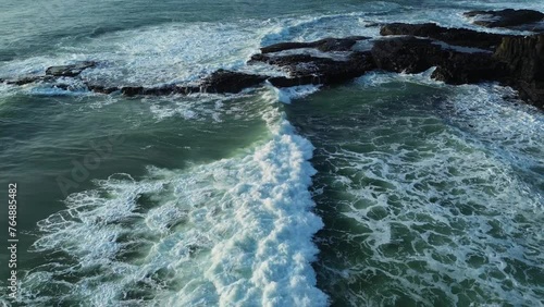 Big ocean waves crashing on cliffs in the morning with aerial view from drone.