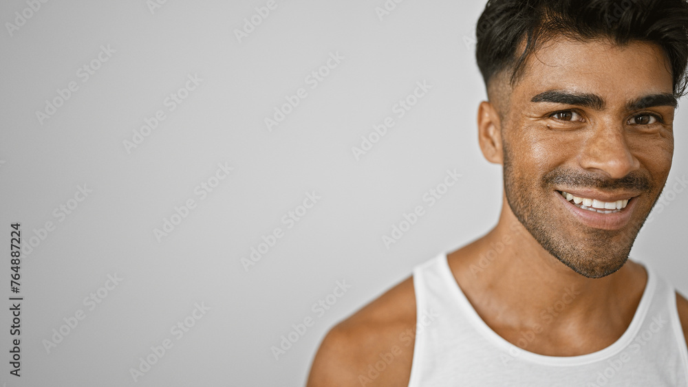 Handsome latino man with beard smiling in white tanktop against isolated white background Handsome latino man with beard smiling in white tanktop against isolated white background