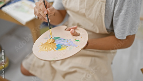 Close-up of a man painting on a palette in a brightly lit studio, showcasing creativity and artistry.