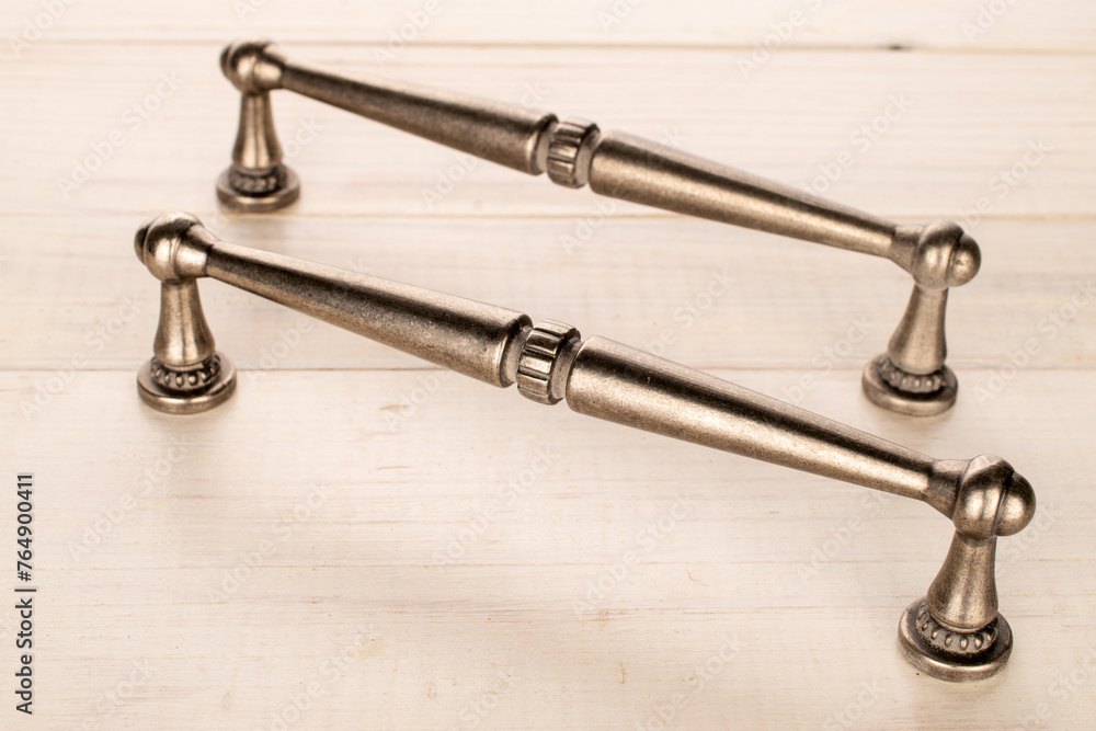 Two metal drawer handles on a wooden table, furniture accessories, macro. Two metal drawer handles on a wooden table, furniture accessories, macro.