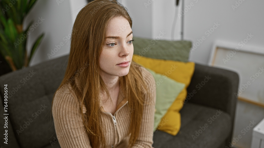 A contemplative young woman sits indoors, exuding a natural beauty in a casual home setting. A contemplative young woman sits indoors, exuding a natural beauty in a casual home setting.