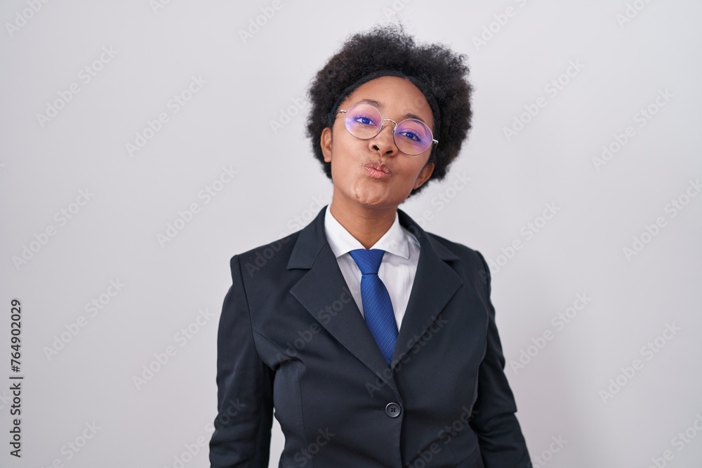 Beautiful african woman with curly hair wearing business jacket and glasses looking at the camera blowing a kiss on air being lovely and sexy. love expression. Beautiful african woman with curly hair wearing business jacket and glasses looking at the camera blowing a kiss on air being lovely and sexy. love expression.