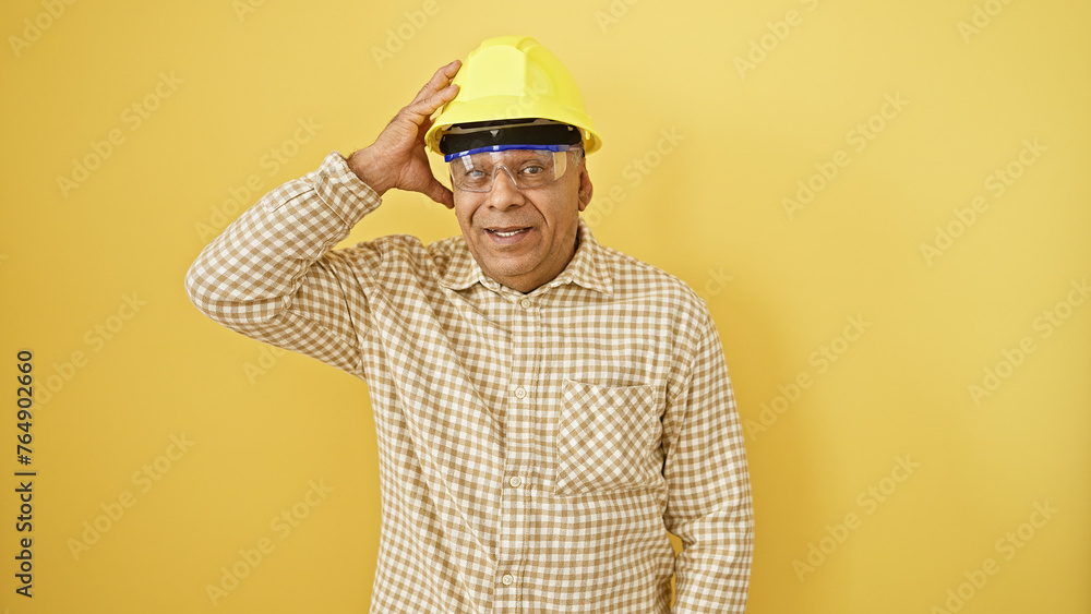 Smiling middle-aged man wearing a hardhat against a yellow background