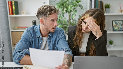 Concerned man and woman with papers discuss work issues in a modern office setting. photo