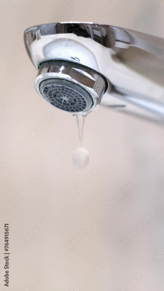 Drop of water drips from the tap. Beautiful fresh and clean water flowing from a tap. Close-up front view slow motion broken chrome faucet in the bathroom. Everyday problems, wasting water and energy. Drop of water drips from the tap. Beautiful fresh and clean water flowing from a tap. Close-up front view slow motion broken chrome faucet in the bathroom. Everyday problems, wasting water and energy.