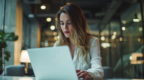 Businesswoman concentrating on her laptop after hours in a dimly lit office