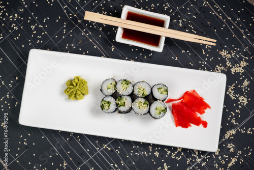 Top view on classic tasty vegetarian kappa maki sushi rolls with fresh cucumbers and rice wrapped in nori on dark background