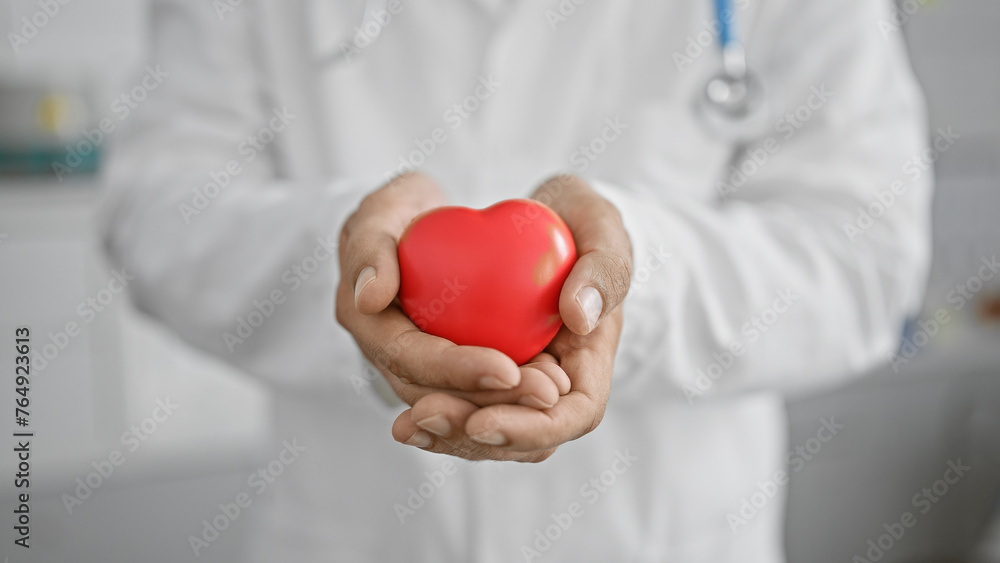 Healthcare professional man in lab coat holding red heart symbol in clinic for cardiology concept