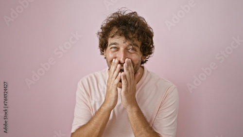 Smiling young hispanic man in casual clothing posing against a pink background  conveying a sense of happiness and positivity.