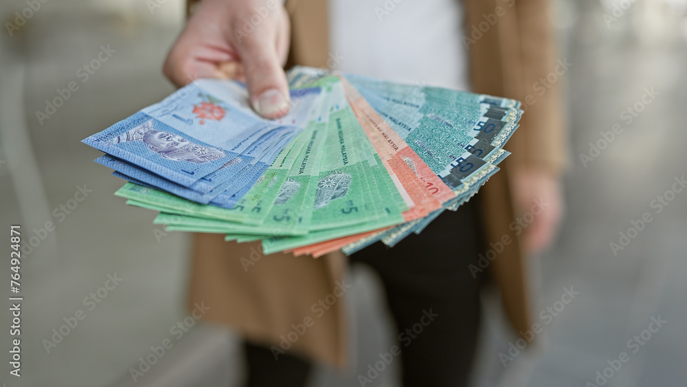 Man holding malaysian ringgit banknotes on an urban street. - obrazy, fototapety, plakaty 