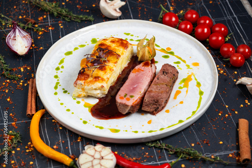 Plate with tender duck breast, potato gratin and various vegetables