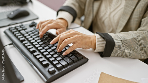 Mature woman typing on a keyboard in an office setting, reflecting everyday professional life.
