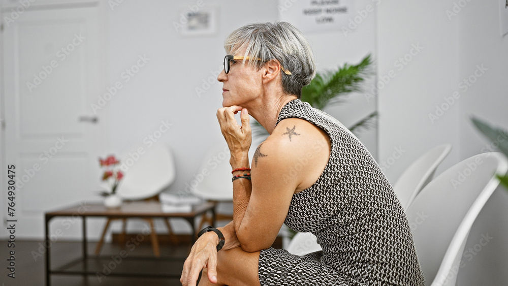 Mature hispanic woman with grey hair and glasses, pondering in a modern indoor setting. Mature hispanic woman with grey hair and glasses, pondering in a modern indoor setting.