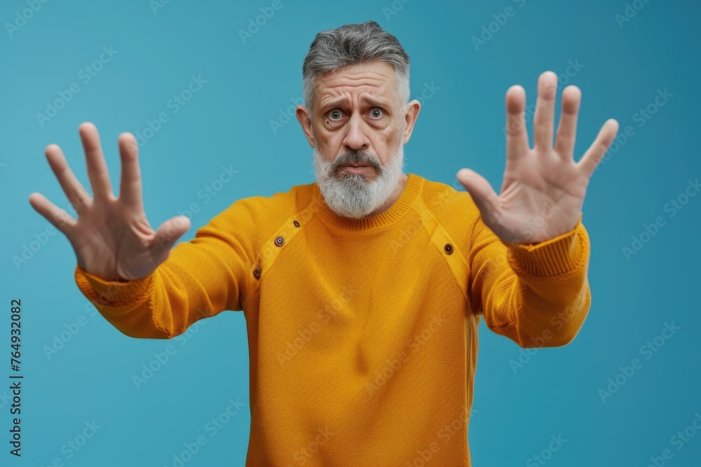 Naklejka premium Mature man showing stop gesture expressing fear and defense.