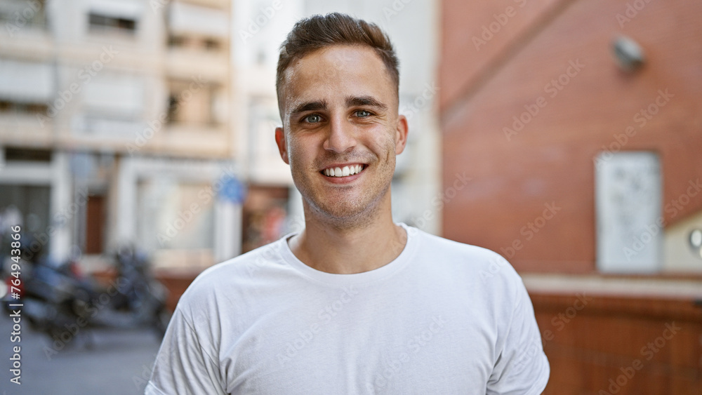 A smiling young hispanic man stands casually on a sunny city street, exuding urban charm and approachability. A smiling young hispanic man stands casually on a sunny city street, exuding urban charm and approachability.