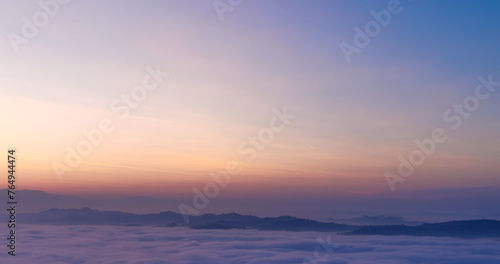 Un mare di nebbia e nuvole al tramonto riempie le valli sotto le montagne photo