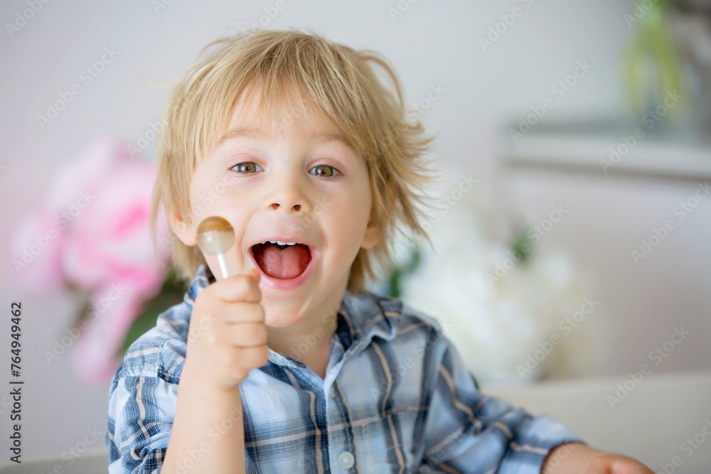 Little toddler child, blond boy, licking lollipop while watching movie on tablet Little toddler child, blond boy, licking lollipop while watching movie on tablet