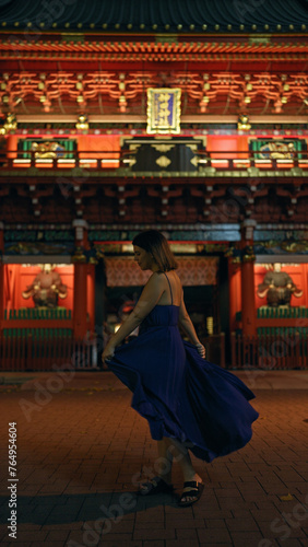 Enchanting night in tokyo, beautiful hispanic woman captured spinning around in a dress at a traditional japanese temple