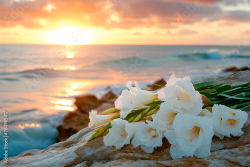 Black funeral ribbon and white gladioli flowers on a rock by the calm sea