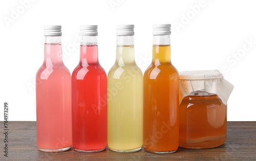 Delicious kombucha in glass bottles and jar on wooden table against white background