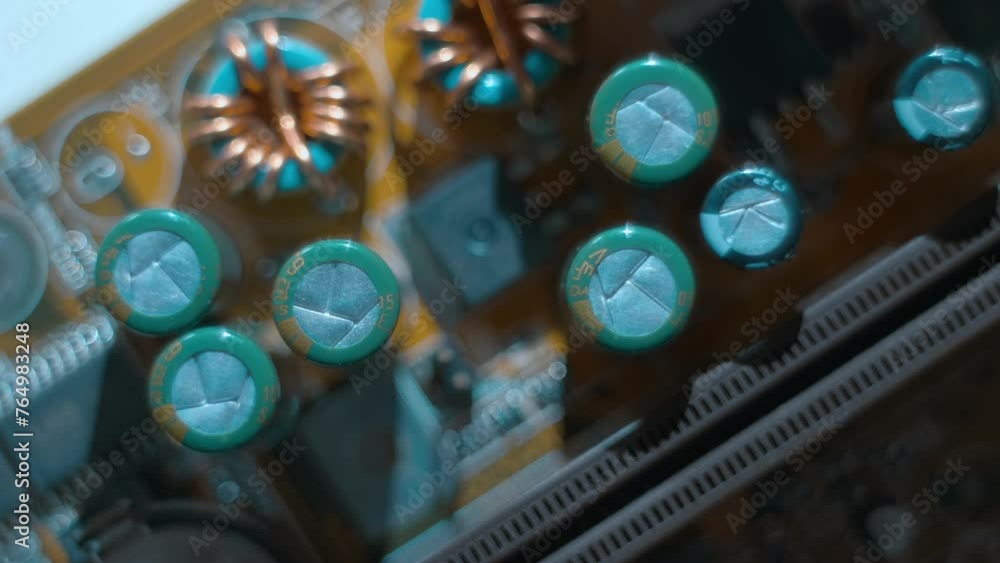 A printed circuit board with many capacitors, coils and other radio components that cast shadows that follow the light source. Closeup. Macro A printed circuit board with many capacitors, coils and other radio components that cast shadows that follow the light source. Closeup. Macro