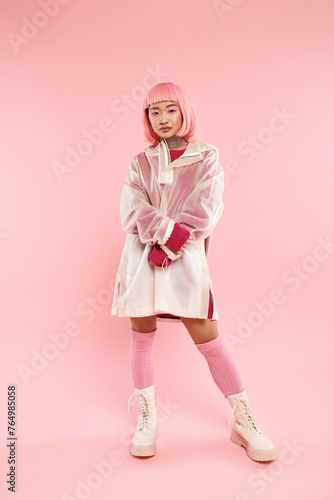 attractive asian young woman with pink hair and makeup in stylish outfit against vibrant background