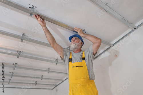 Worker placing aluminum profile for gypsum ceiling and insulation