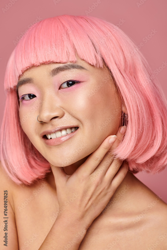 charming woman in 20s with pink hair touching her chin with hand and smiling on vibrant background charming woman in 20s with pink hair touching her chin with hand and smiling on vibrant background