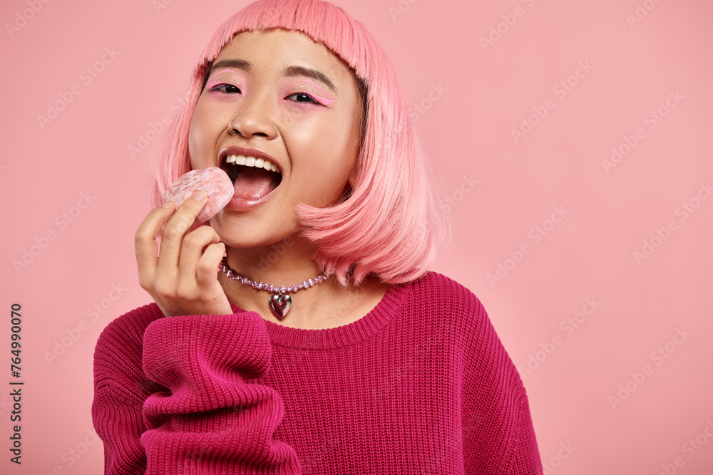 portrait of cheerful asian woman with pink hair eating mochi with admiration on vibrant background portrait of cheerful asian woman with pink hair eating mochi with admiration on vibrant background